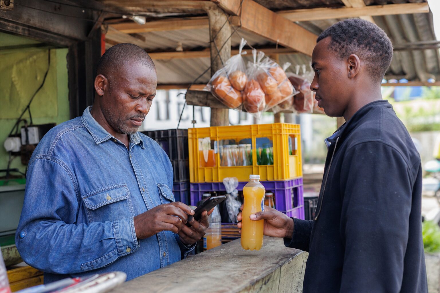 Juice kiosk attendant tapping a phone at the till in the morning
