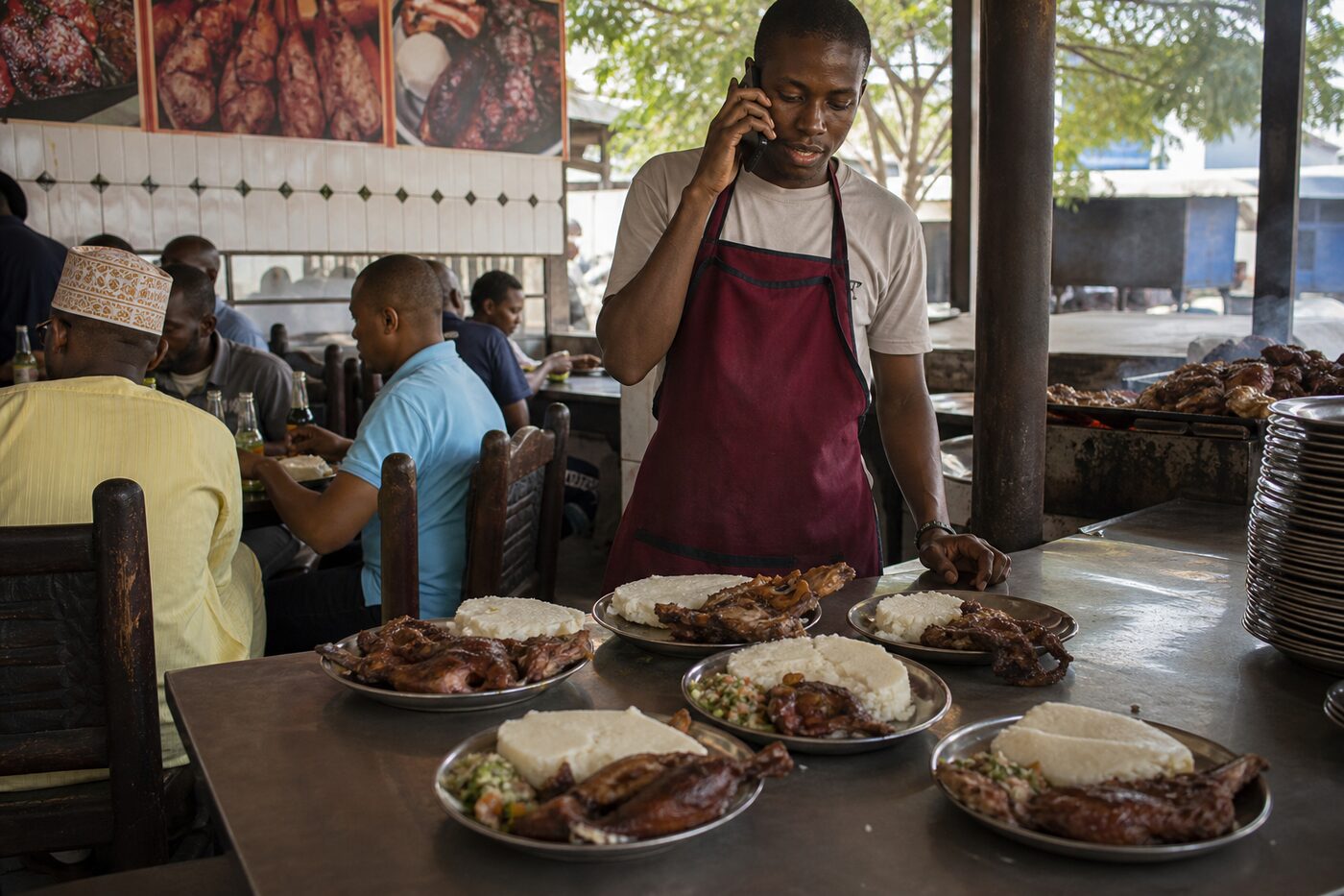 Nyama choma attendant taking an order on a phone at lunch rush